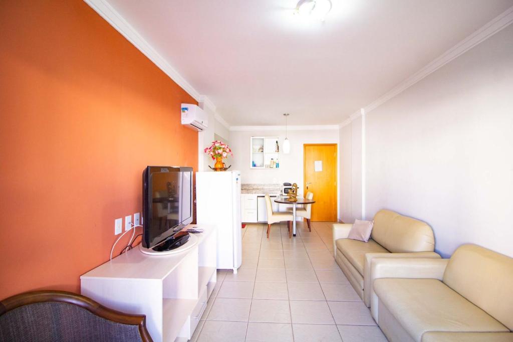 a living room with a couch and a tv at Apart Hotel no Rio Quente- Cond. Águas da Serra in Rio Quente