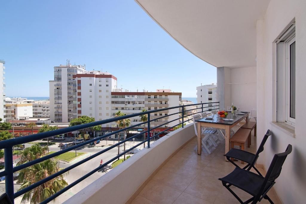 een balkon met een tafel en stoelen en uitzicht op de stad bij Quarteira Beach iii in Quarteira