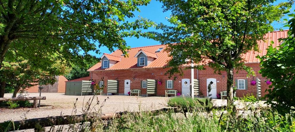un gran edificio de ladrillo rojo con árboles delante de él en Lustrup Farmhouse, en Ribe