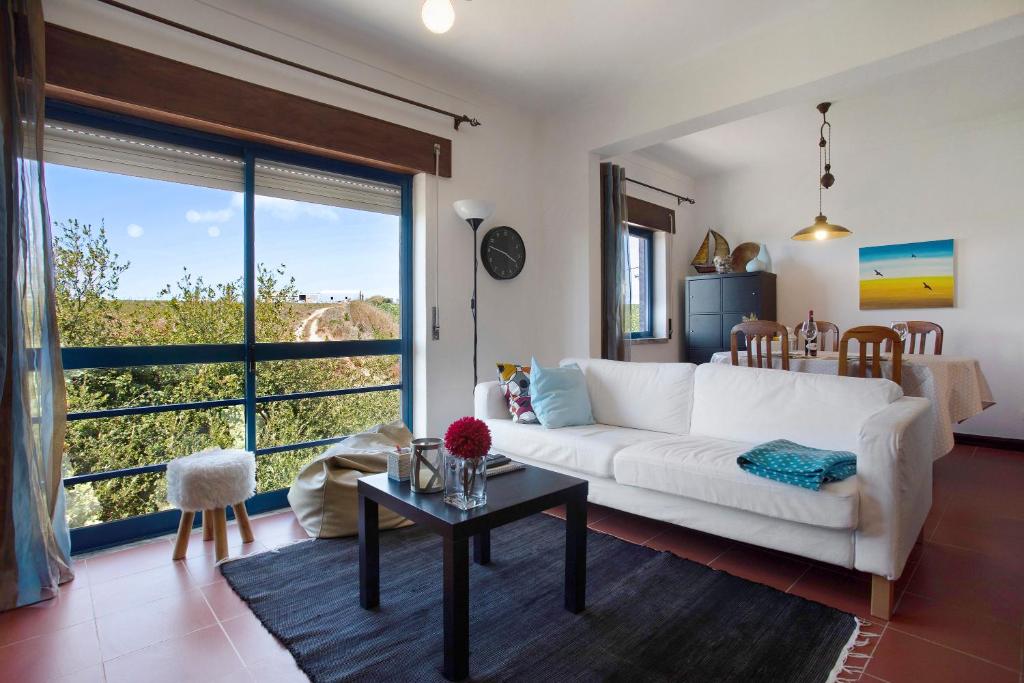 ein Wohnzimmer mit einem weißen Sofa und einem Tisch in der Unterkunft Sao Bernardino Beach House in Atouguia da Baleia