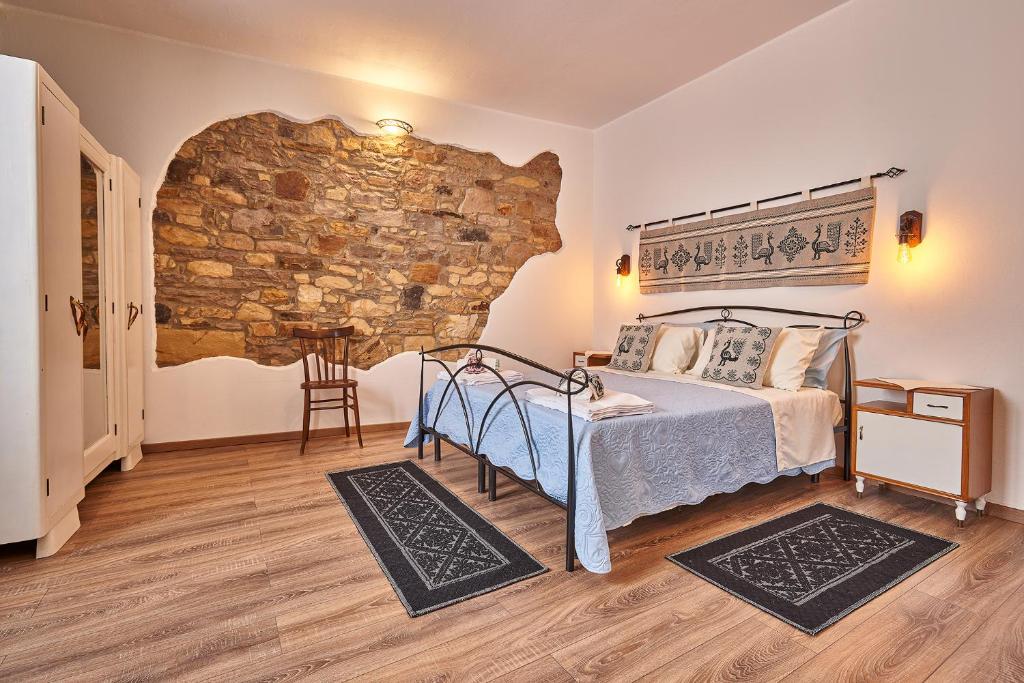 um quarto com uma cama e uma parede de pedra em al VICOLO VI em Sardara