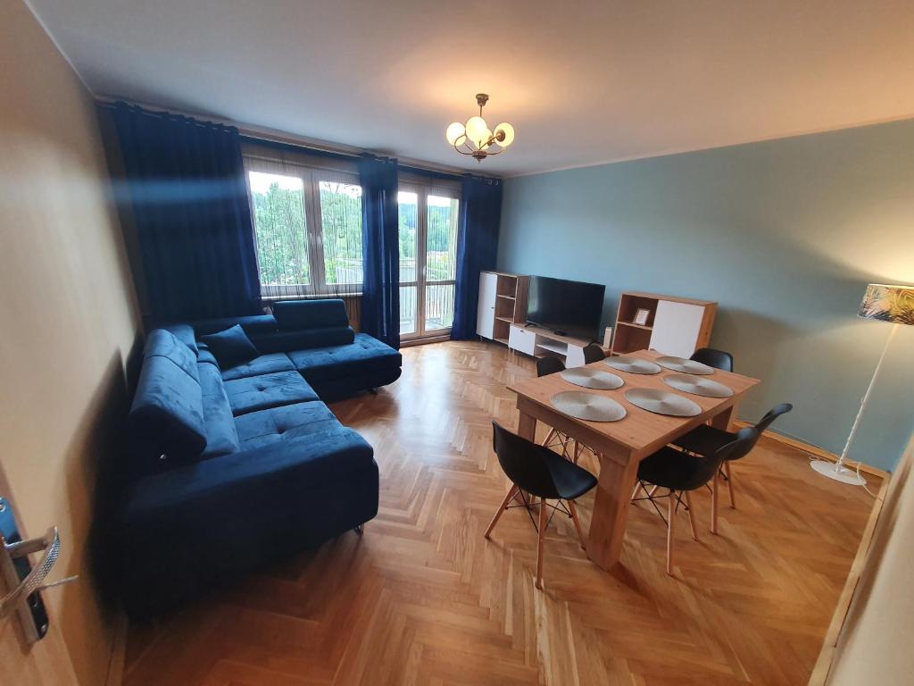 un soggiorno con divano blu e tavolo di Cozy Sunny Apartment a Gdynia