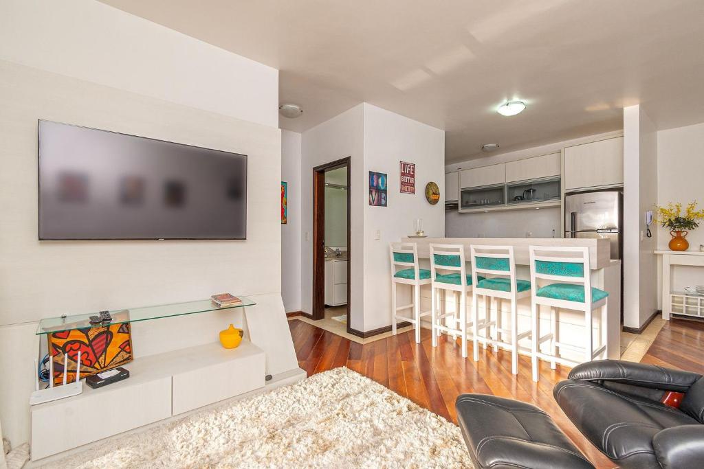 a living room with a couch and a tv on a wall at Apto com banheira de imersão - Stay House in Canela