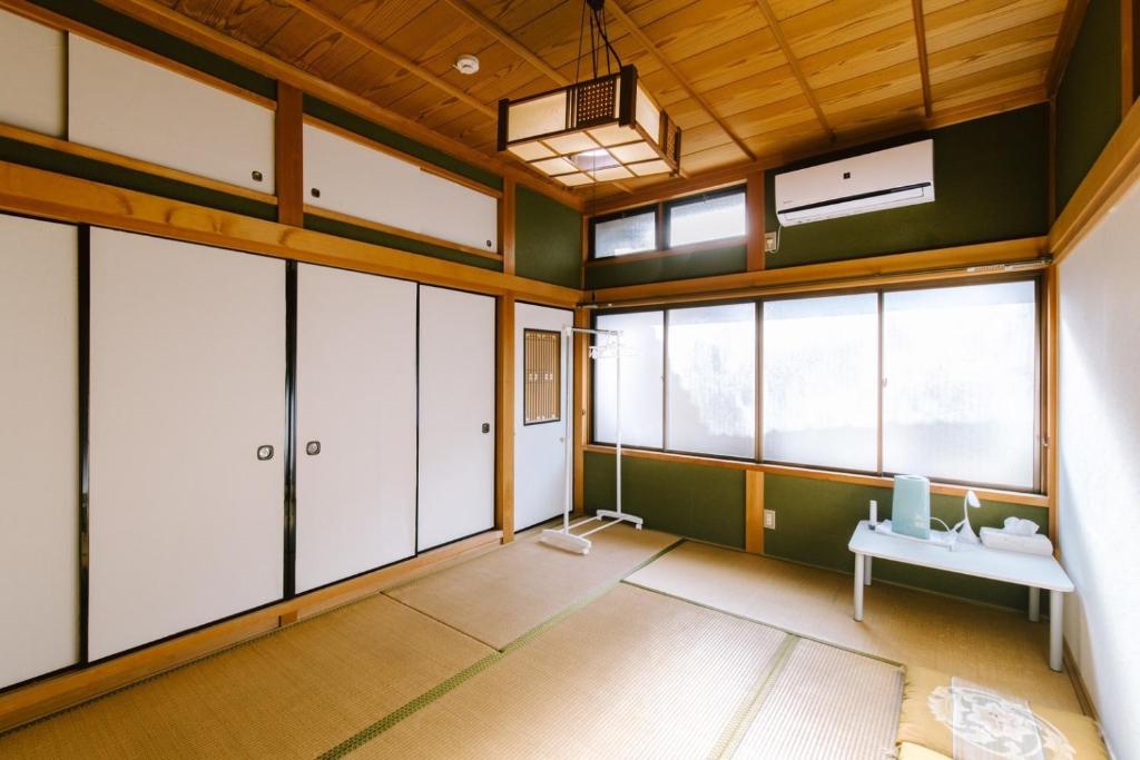 um quarto com paredes e janelas verdes e uma secretária em SUSAMI LIFE HAUS - Vacation STAY 85652v em Esumi