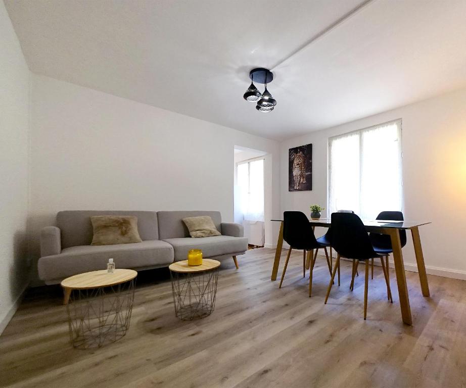 a living room with a couch and a table and chairs at Appartement au coeur de Cours La Ville in Cours la Ville