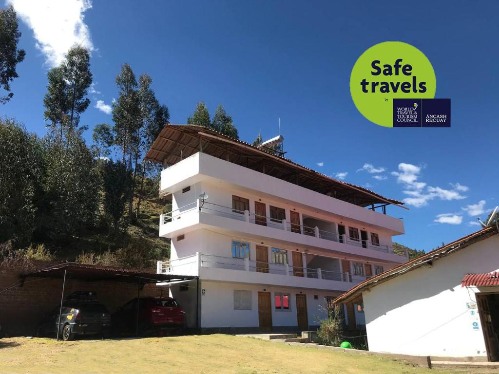 Un bâtiment blanc avec une voiture garée devant. dans l'établissement Hacienda Norabuena, à Recuay