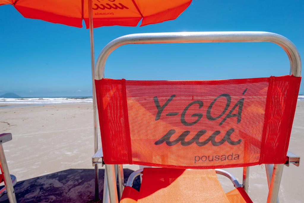 a red chair sitting on the beach next to an umbrella at Pousada Y-Goá in Bertioga