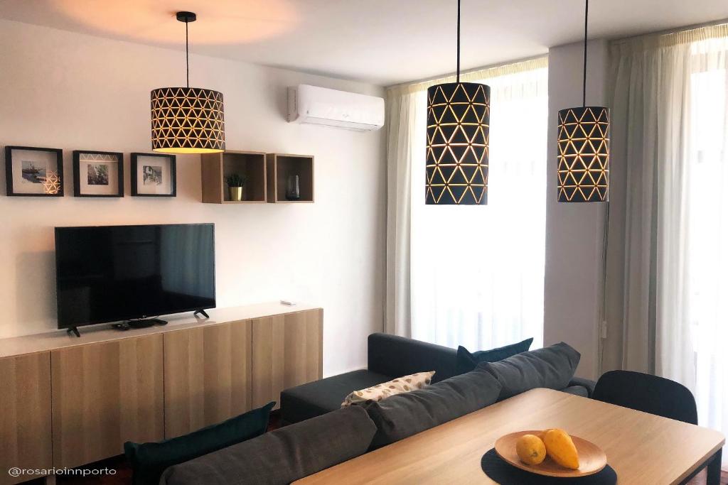 een woonkamer met een bank en een televisie bij rosario inn porto in Porto