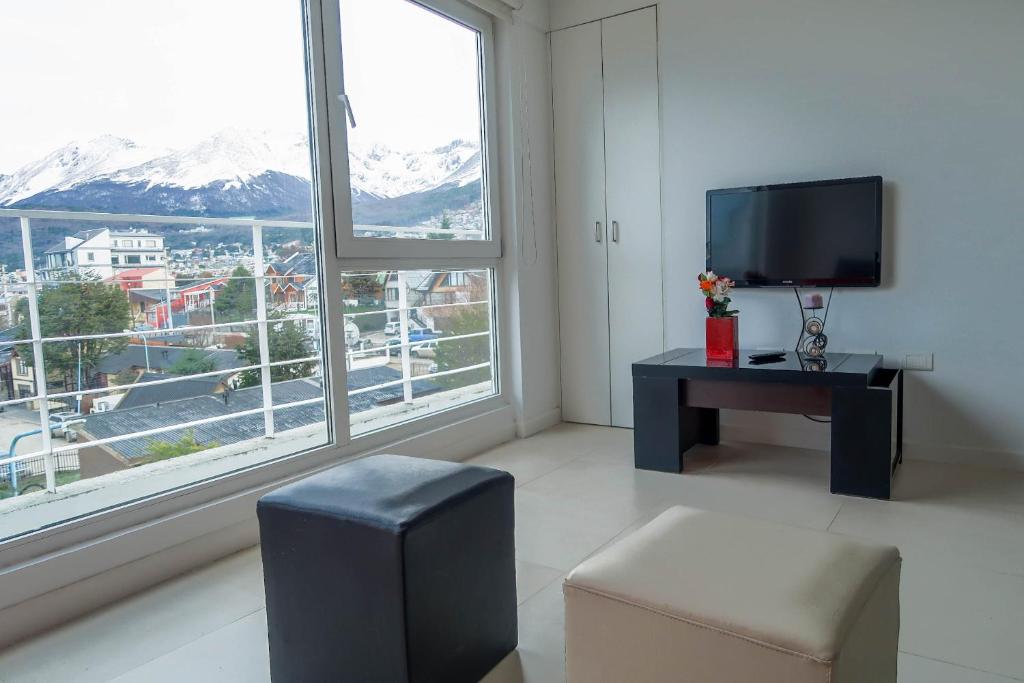 uma sala de estar com uma televisão, uma mesa e uma janela em Josefina em Ushuaia