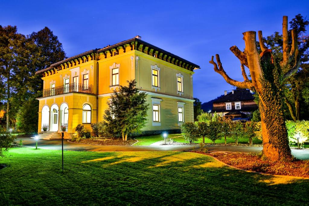 une grande maison jaune avec un arbre en face dans l'établissement Villa Aurelie, à Velké Losiny