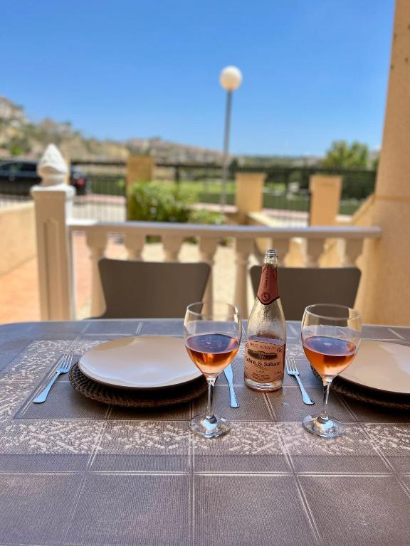 un tavolo con due bicchieri e una bottiglia di vino di Tranquil Self Catering Golf Course Apartment ad Alicante