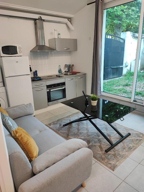un salon avec un canapé et une cuisine dans l'établissement APPARTEMENT JARDIN, à Parc Saint-Maur