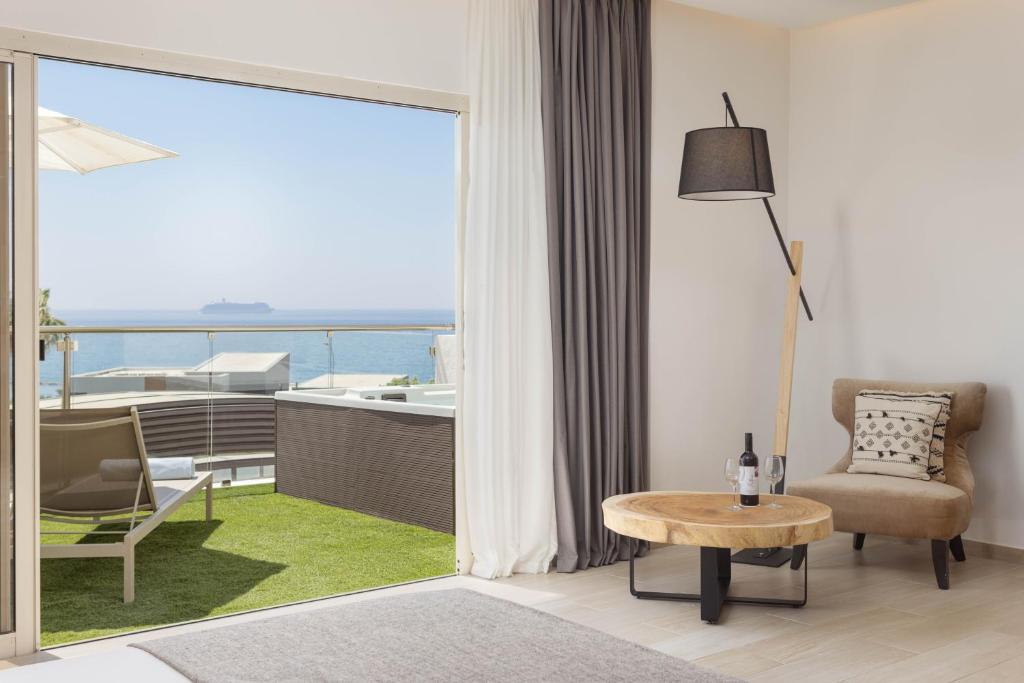 a living room with a table and a view of the ocean at Atlantica Bay - Adults Only in Limassol