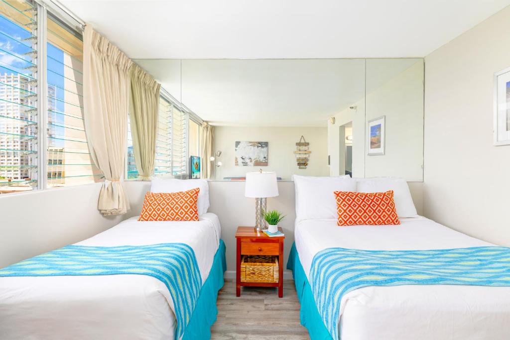 Dos camas en una habitación con dos ventanas. en Cozy Waikiki Studio at Aqua Aloha Surf, en Honolulu