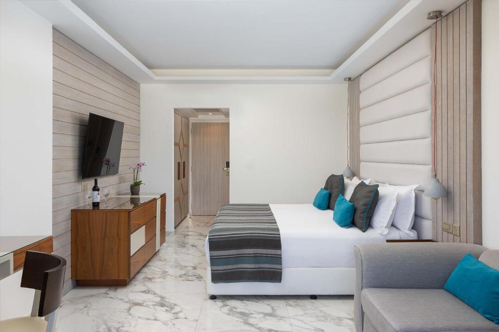 a hotel room with a bed and a couch at Atlantica Bay - Adults Only in Limassol