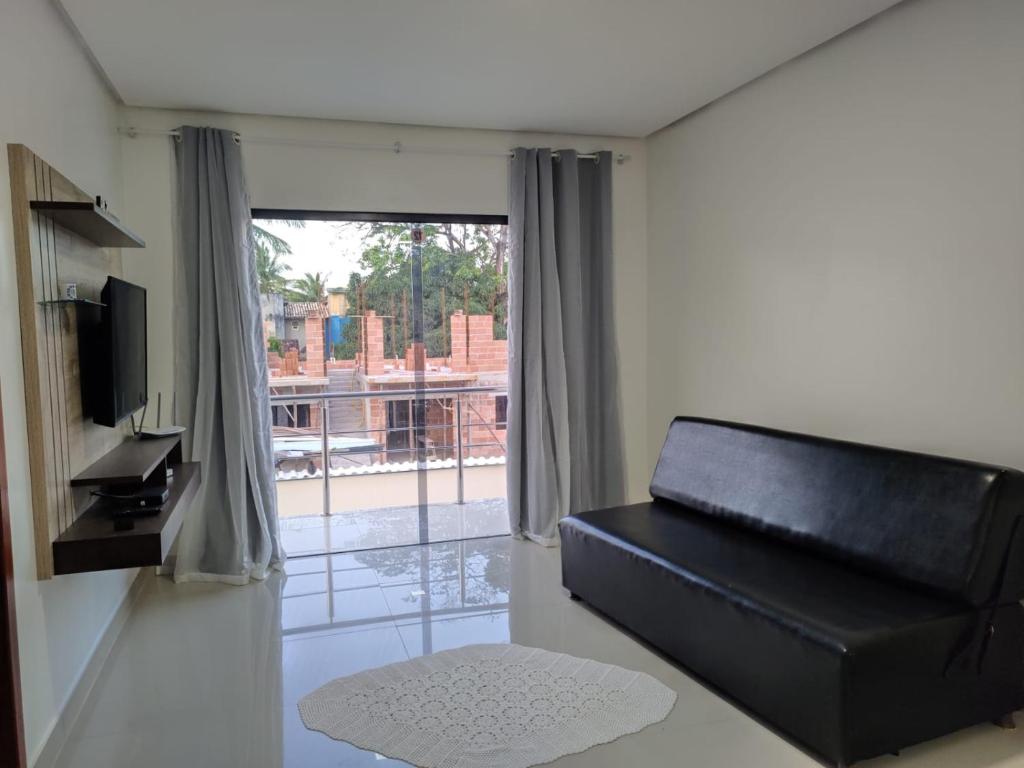 ein Wohnzimmer mit einem schwarzen Ledersofa und einem Fenster in der Unterkunft TAPERAPUAN in Porto Seguro