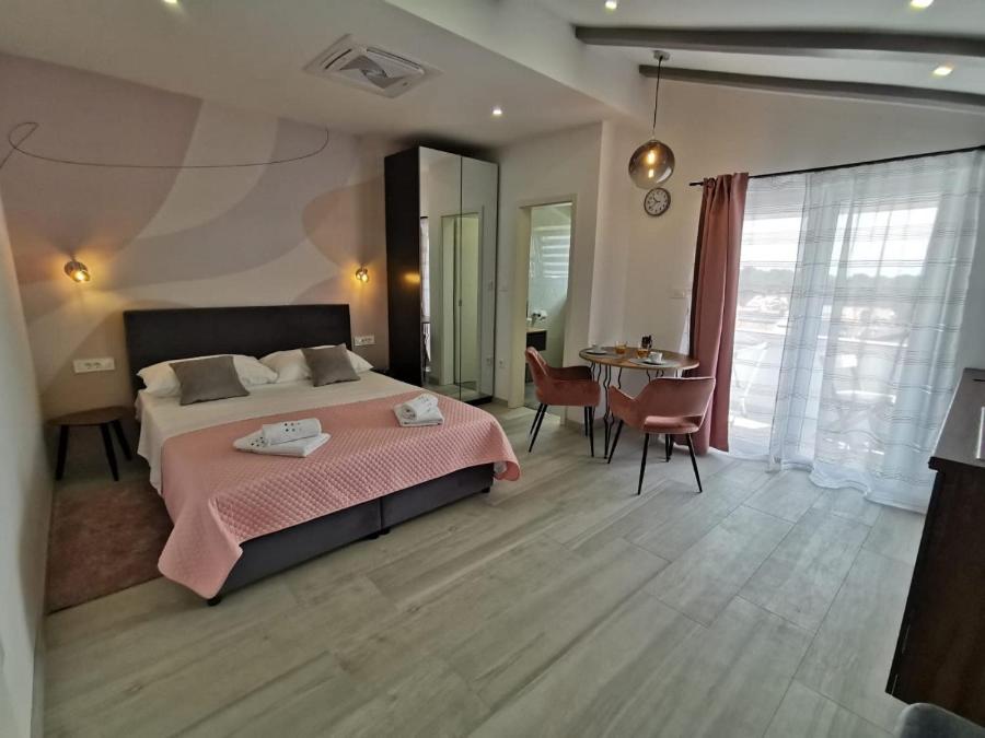 1 dormitorio con 1 cama y 1 mesa con sillas en New Nikolina 4 star en Mali Lošinj