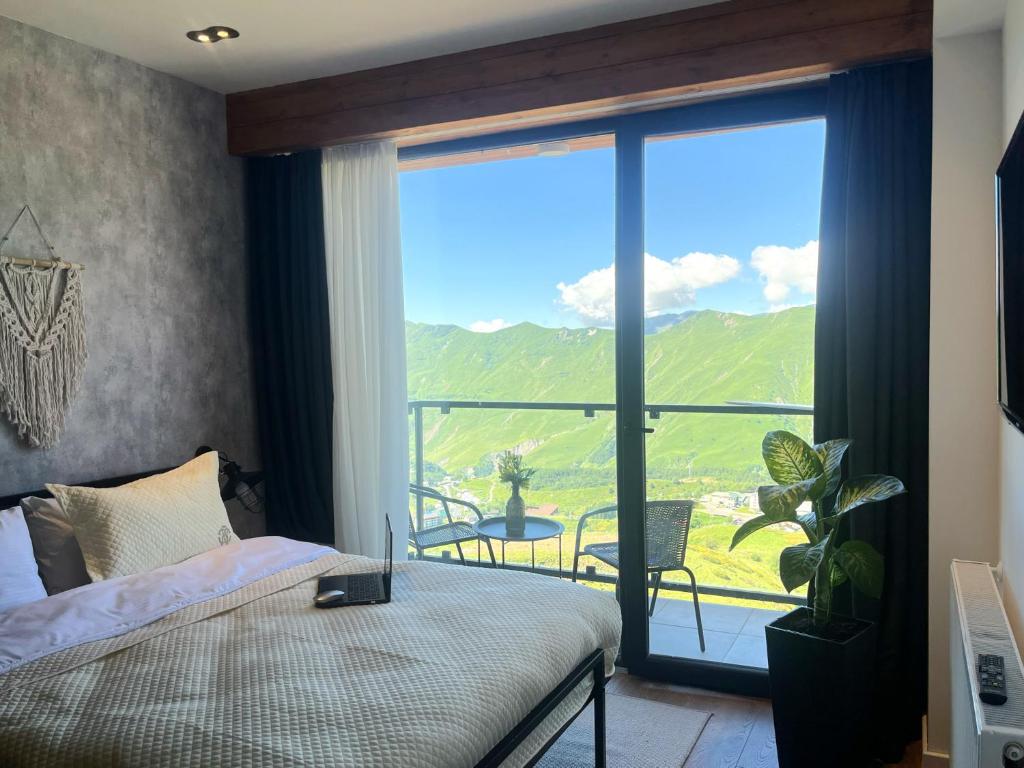 een slaapkamer met een bed en een groot raam bij Stuning views on mountains, gudauri in Goedaoeri