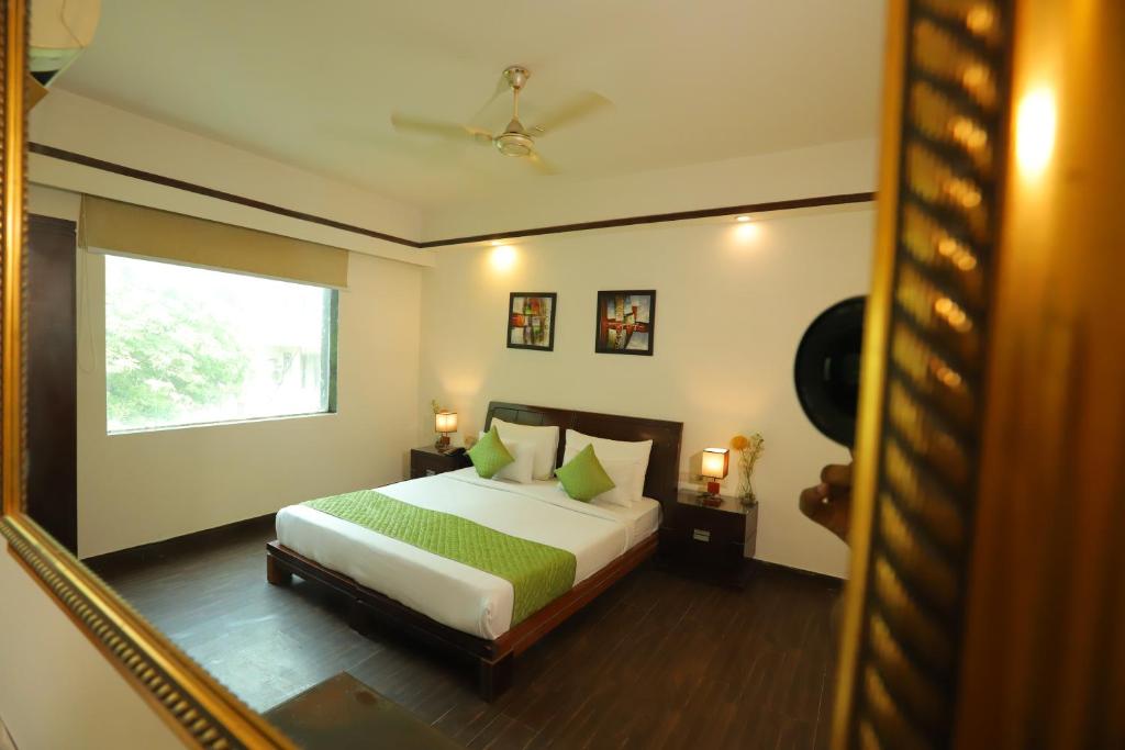 sypialnia z łóżkiem z zieloną pościelą i oknem w obiekcie Hotel Mayur Assam - New Delhi Railway Station w Nowym Delhi