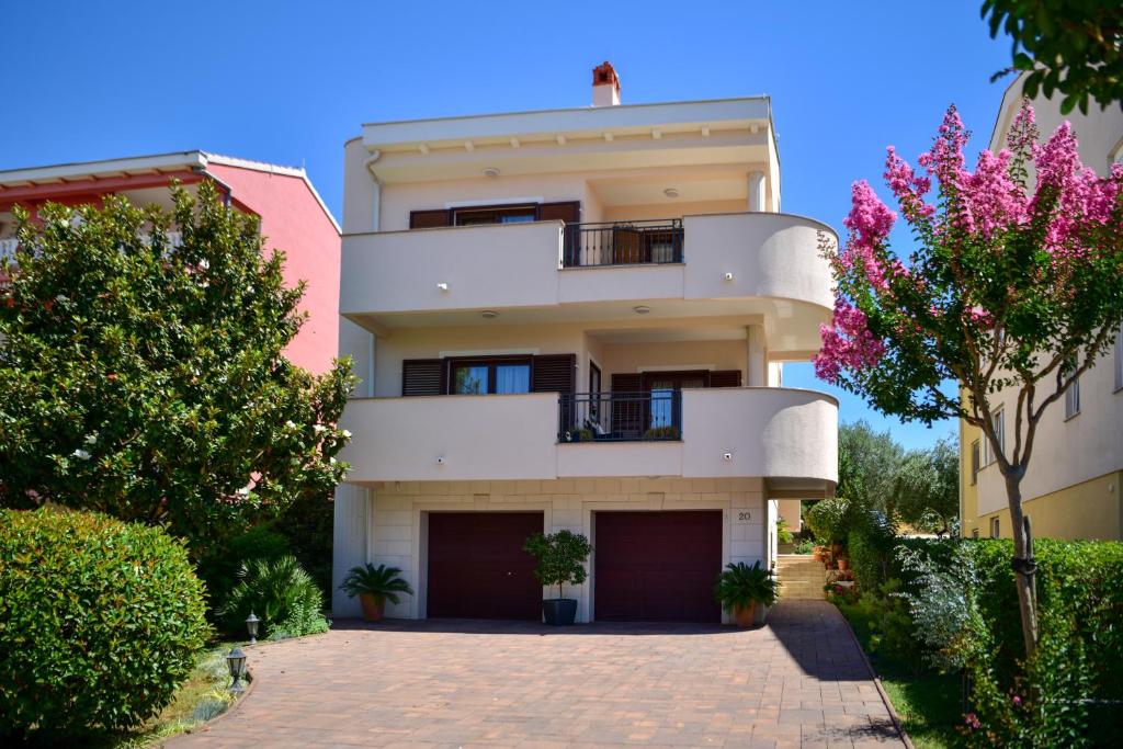 a large white building with a balcony and trees at Apartments Villa Nataly in Zadar