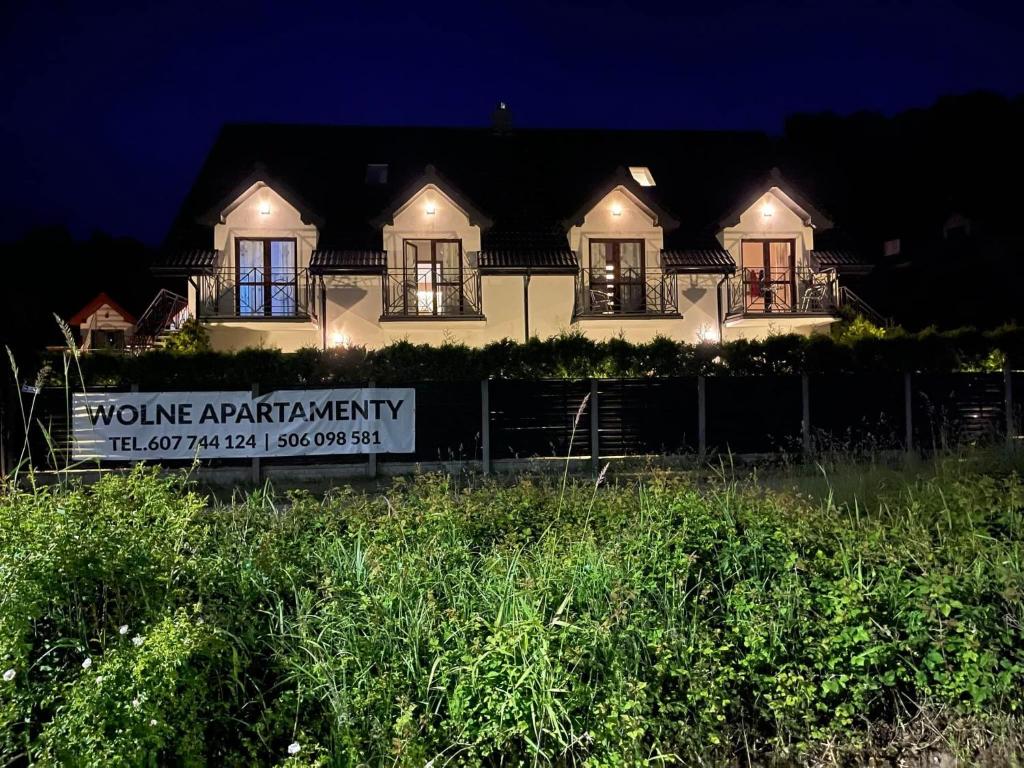 a house at night with a sign in front of it at Baltic Trio Apartaments - Rusinowo in Rusinowo