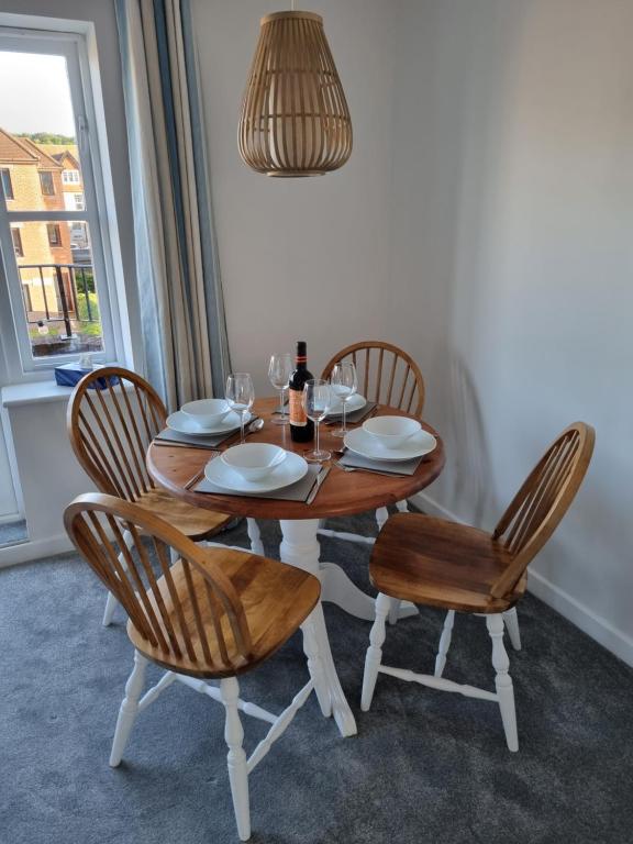 a wooden table with chairs and a bottle of wine at HighTide - 2 bed with parking, balcony & sea view. in Swanage