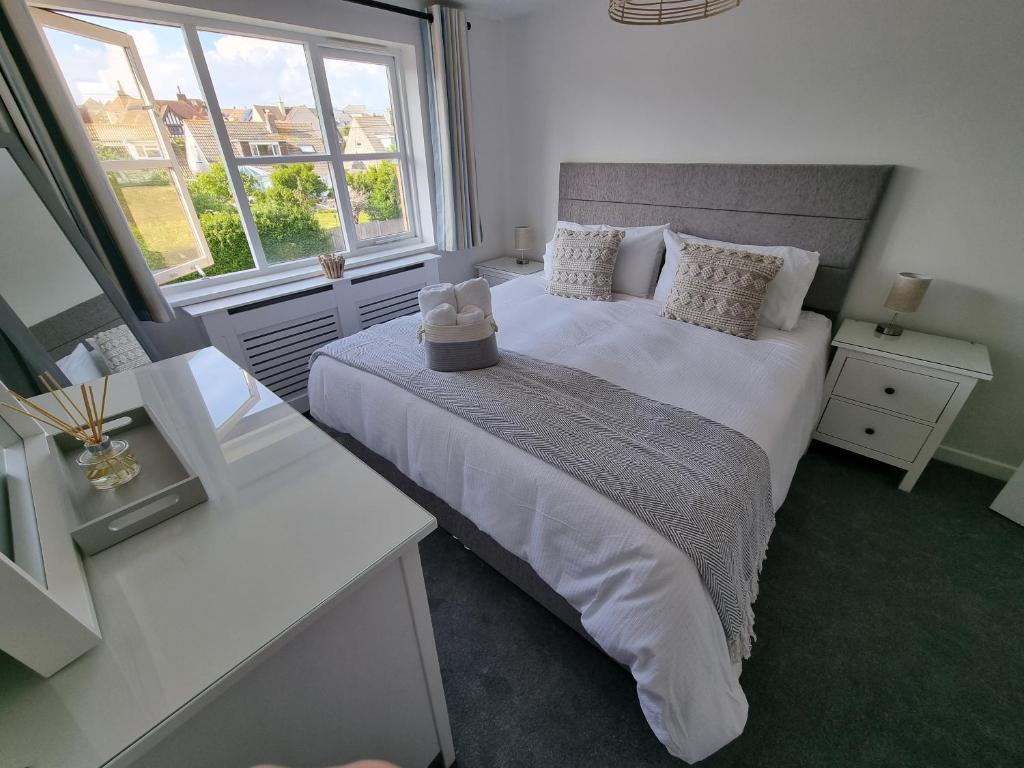 a bedroom with a large bed and two windows at HighTide - 2 bed with parking, balcony & sea view. in Swanage