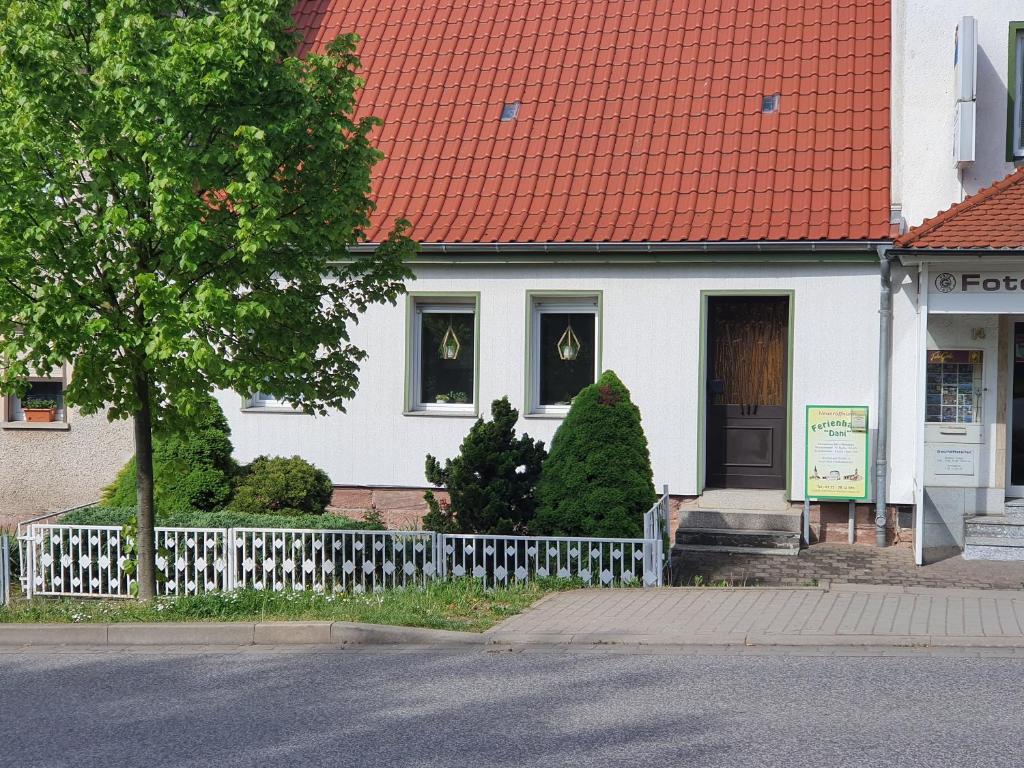 une maison blanche avec un toit orange et une clôture dans l'établissement Ferienhaus Dani, à Bad Frankenhausen