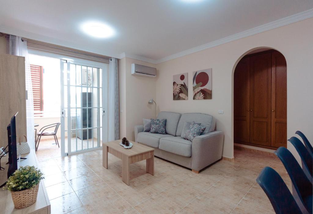a living room with a couch and a table at Apto ACHE, acogedor apartamento de 66 m con terraza, aire acondicionado y parking privado gratuito in Los Abrigos