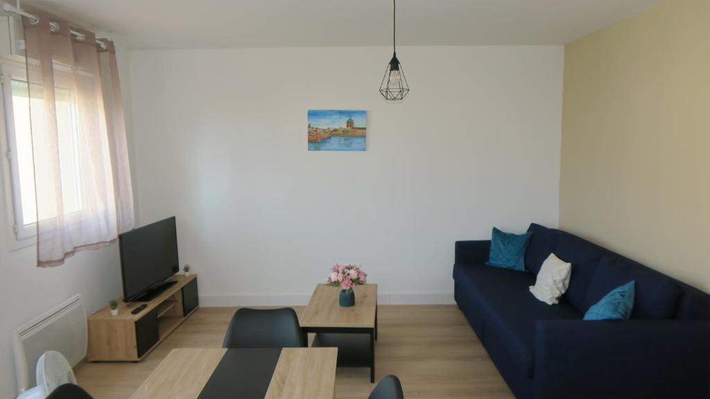 een woonkamer met een blauwe bank en een tafel bij Appartement chaleureux et élégant en résidence. in Labastidette
