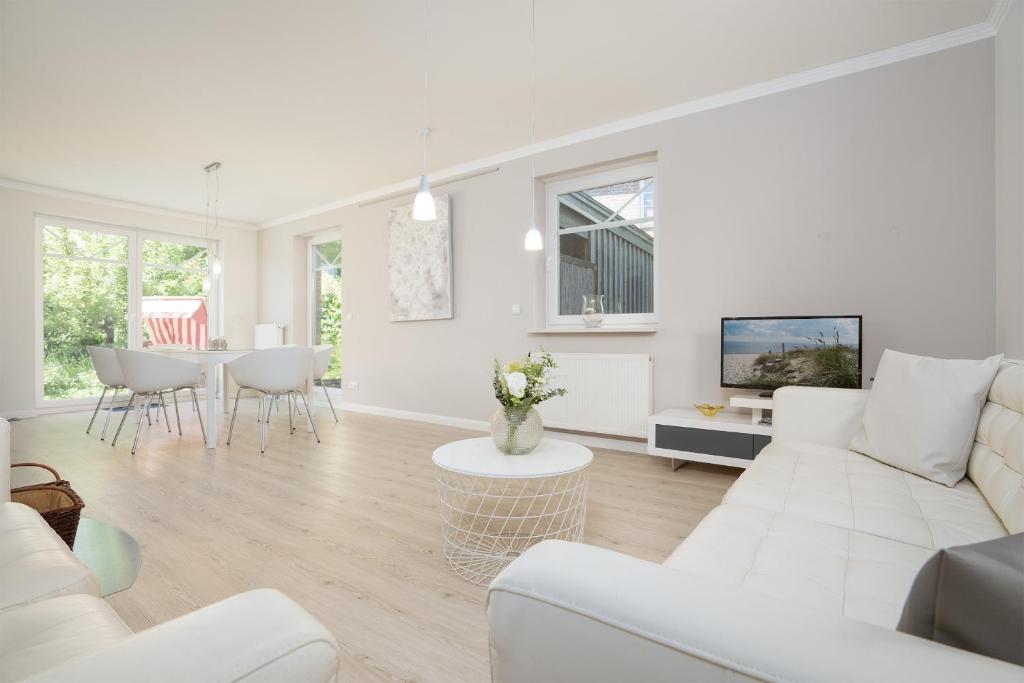 a white living room with a white couch and a table at Haus Sommerzeit 