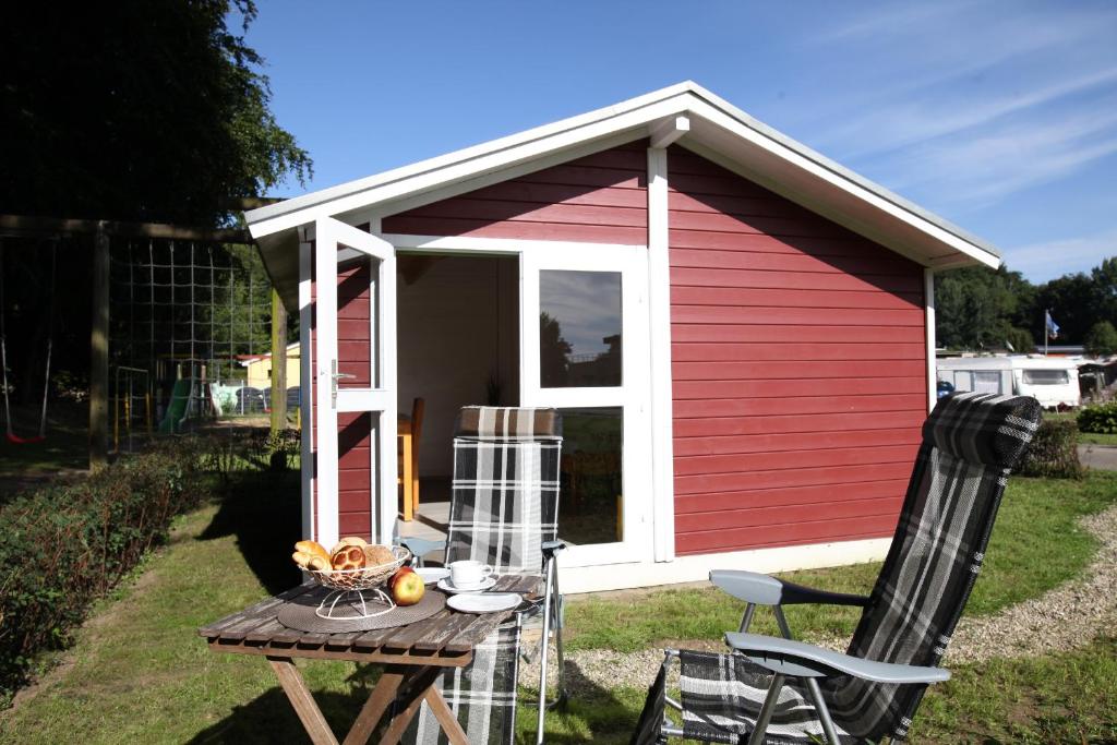 einen roten und weißen Schuppen mit einem Tisch und Stühlen in der Unterkunft Ostseecamp Lübecker Bucht Wanderhütte in Scharbeutz