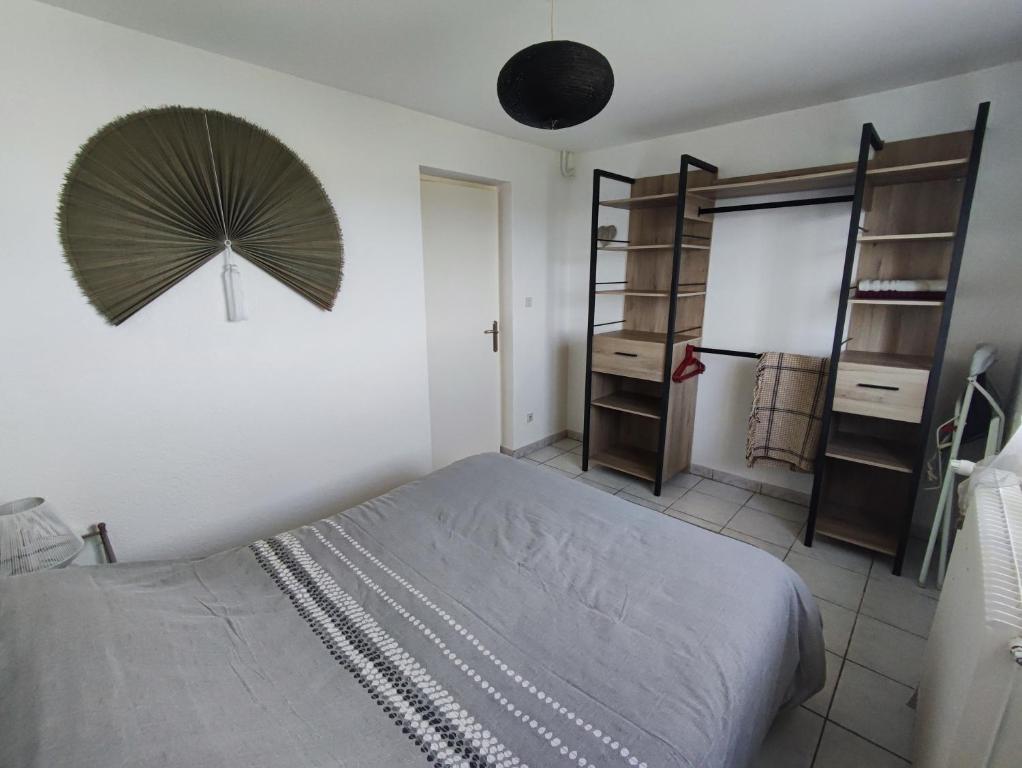 um quarto com uma cama e uma ventoinha na parede em Appartement Abadie em Bagnères-de-Bigorre