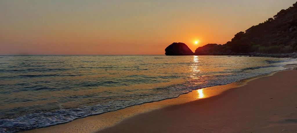 a sunset on a beach with the sun setting at BOHALI'S HOUSE in Agios Gordios