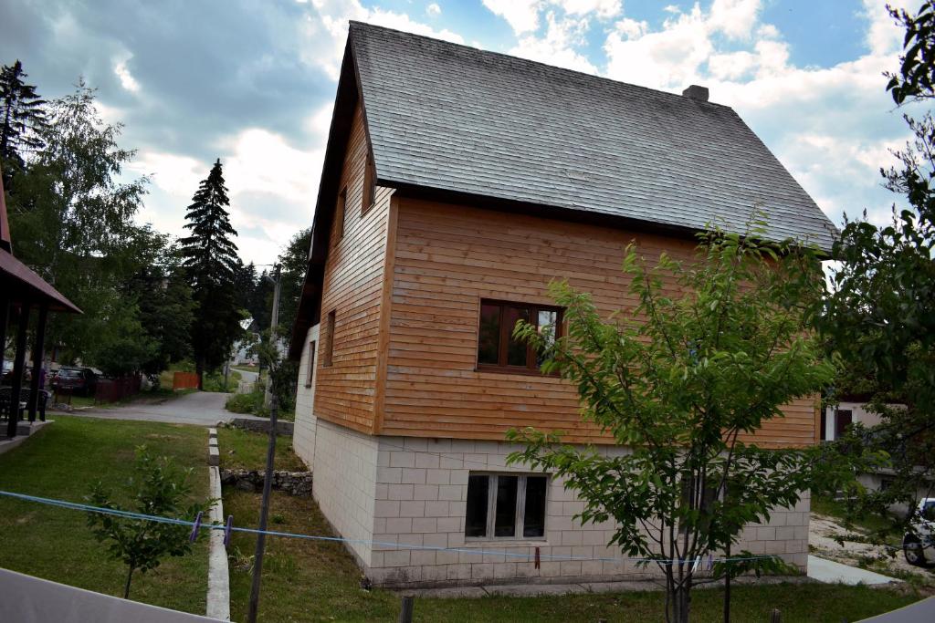a large wooden house with a gambrel roof at Srna Chalet - Rooms in Žabljak