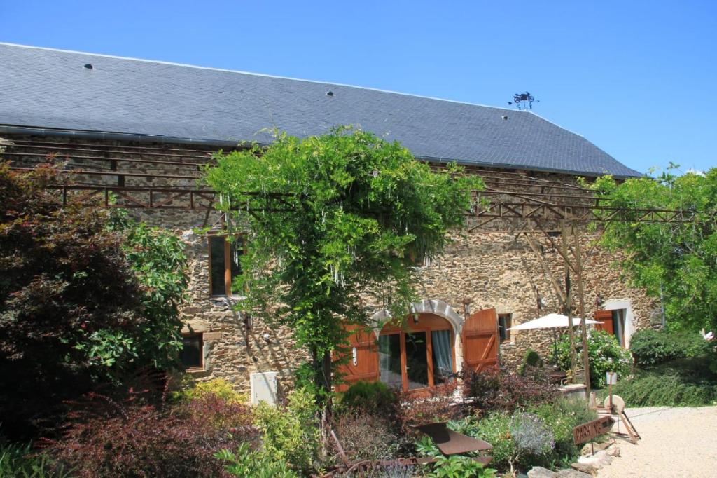 a stone house with a tree in front of it at La Vieille Grange avec piscine et jardin in Prévinquières