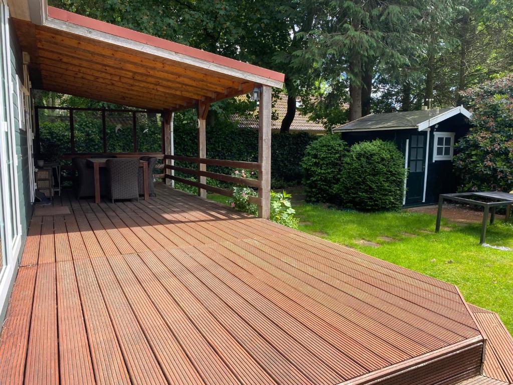 una terraza de madera en el lateral de una casa en Ruim privacyvol chalet met overdekt terras, en Ermelo