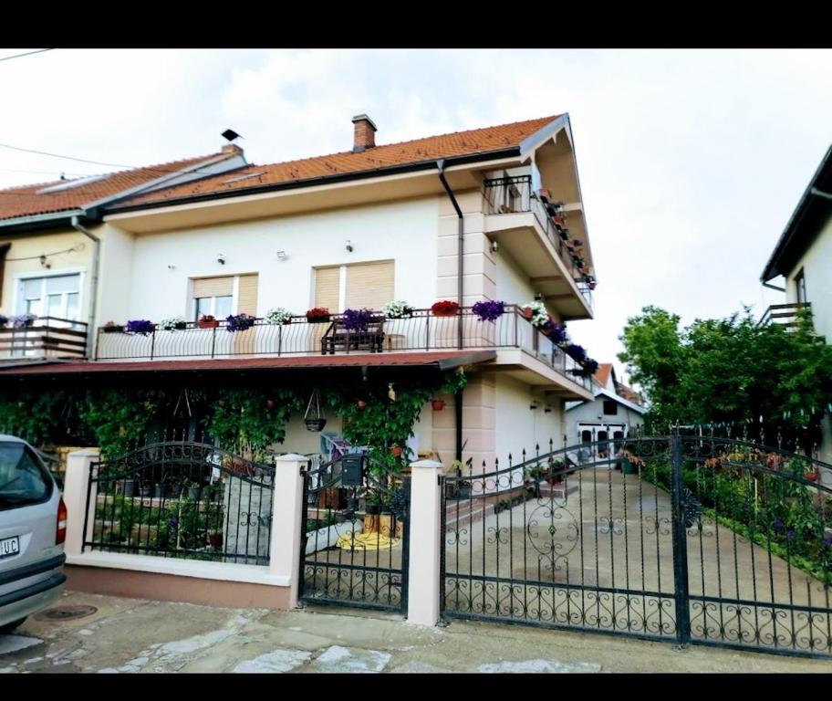 Privatni smestaj - Rooms في Dobrosin: منزل أبيض مع الزهور على الشرفة