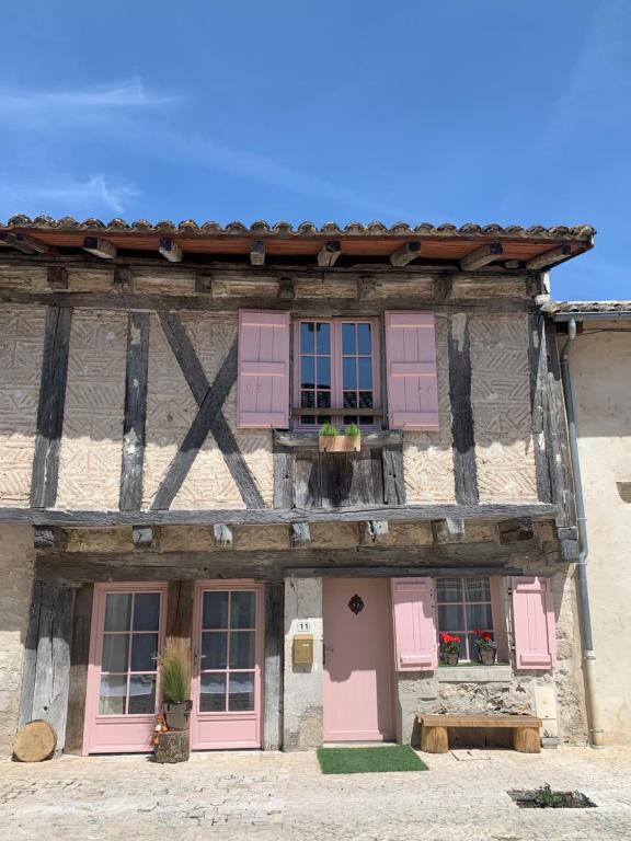 un ancien bâtiment avec des portes et des fenêtres roses dans l'établissement Gite Oranis, maison de charme au cœur du Quercy blanc!, à Monjoi