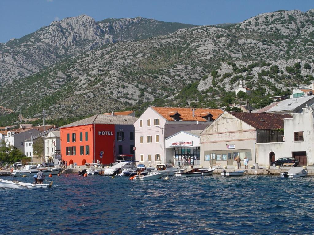 a town with boats in the water with a mountain at Hotel Palace Vrkljan in Karlobag