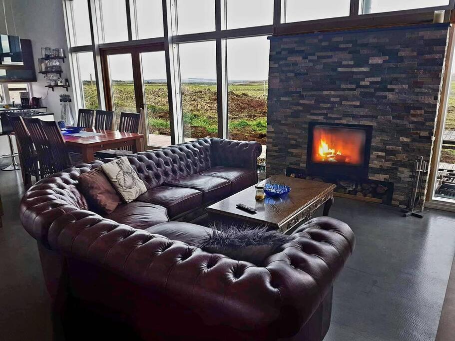 a living room with a leather couch and a fireplace at Luxury home surronded with extraordinary nature in Selfoss