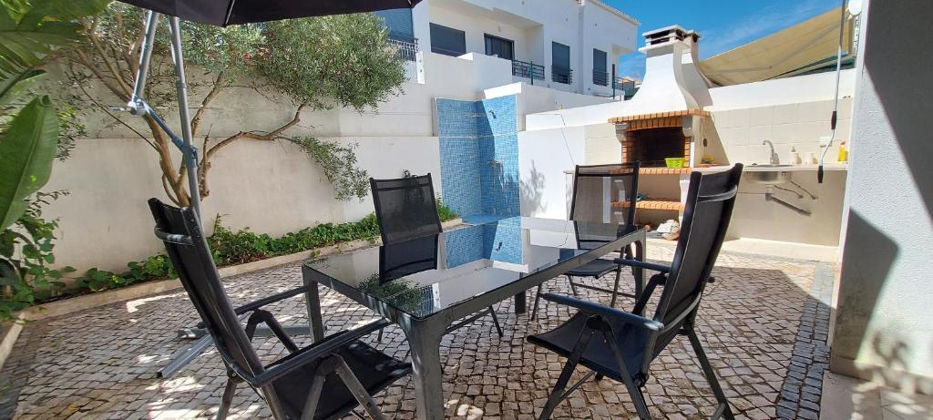 uma mesa e duas cadeiras e um guarda-sol em Casa Sal Sol Sul - casa de férias perto da praia da Manta Rota em Vila Nova de Cacela