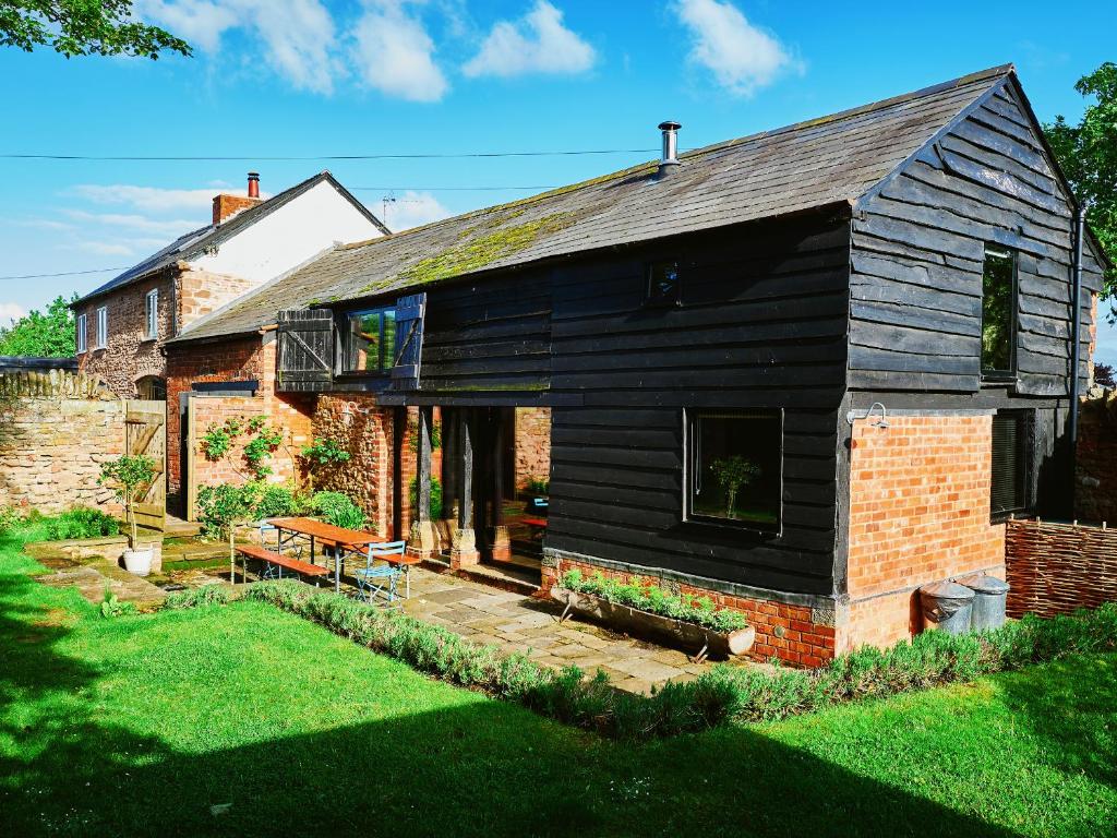 a house with a black roof and a brick building at The Hayloft in Ross on Wye