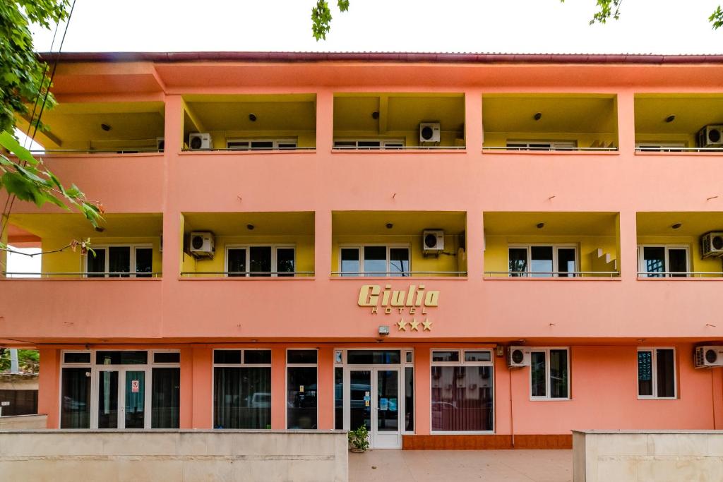 un gran edificio anaranjado con el letrero del gulum. en Hotel Giulia, en Eforie Nord