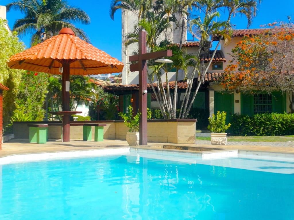 VIVA BUZIOS no Condominio Aqua Marina casa13 في بوزيوس: مسبح فيه مظله ومبنى