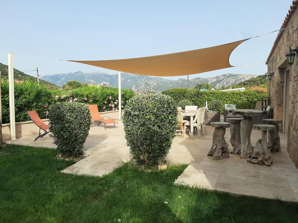 eine Terrasse mit einem Tisch, Stühlen und einem Sonnenschirm in der Unterkunft Orasi Sartène Gîte Casa Fiurita in Sartène