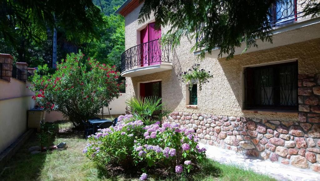 ein Haus mit einem rosa Fenster und ein paar Blumen in der Unterkunft Appartement 48 m2 avec jardin au rdc dans villa à 5 min à pied des Thermes de Vernet-les-Bains, location de samedi à samedi in Vernet-les-Bains