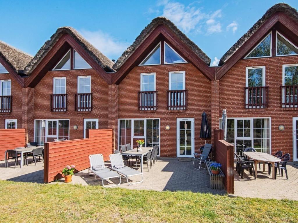 un bâtiment en briques avec des tables et des chaises devant lui dans l'établissement Holiday home Rømø CXXV, à Kongsmark