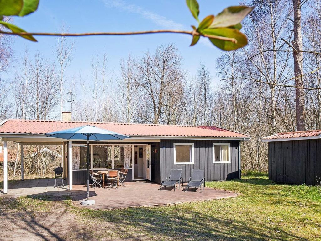 a house with a patio with a table and an umbrella at Holiday home Aakirkeby XXVII in Vester Sømarken