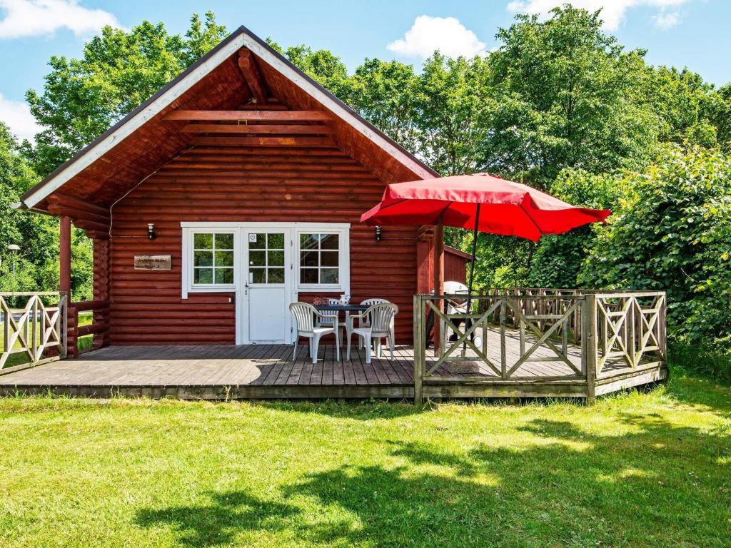 a cabin with a deck with a table and an umbrella at Holiday home Hovborg VII in Hovborg